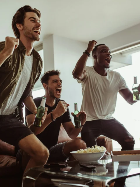 Friends cheering while watching a match at home