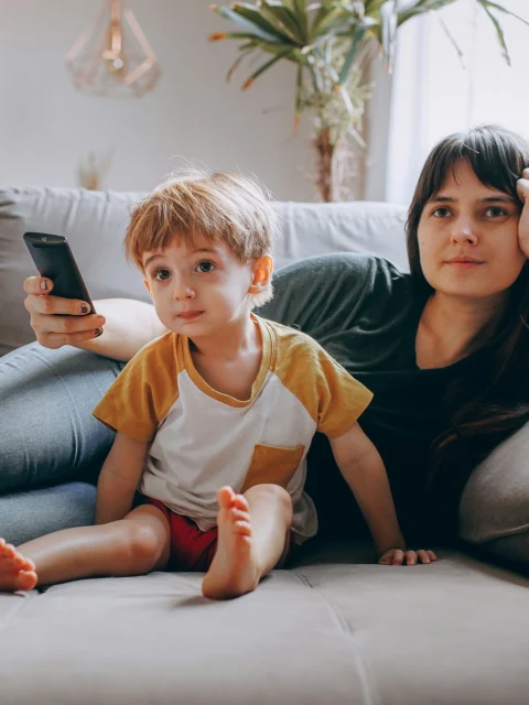 Parent and child watching TV on the sofa