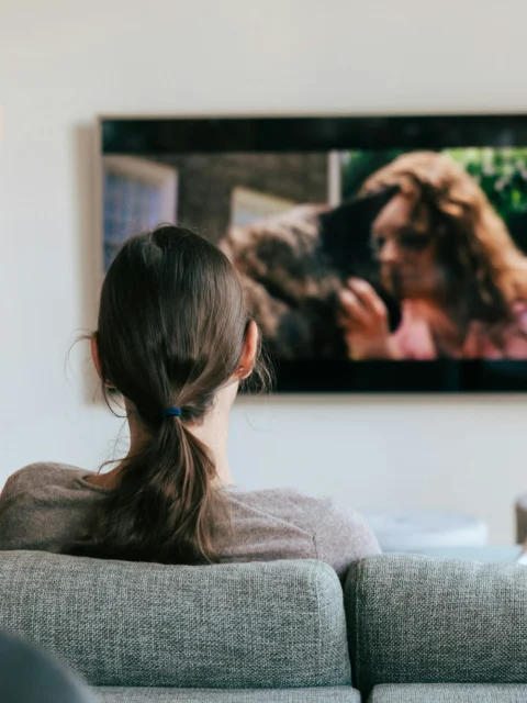 Two people on a sofa watching a large wall-mounted TV
